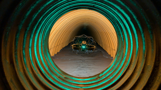 Photo looking into a long tunnel, a drone is seen mid-air facing the camera. The drone is scanning the tunnel.