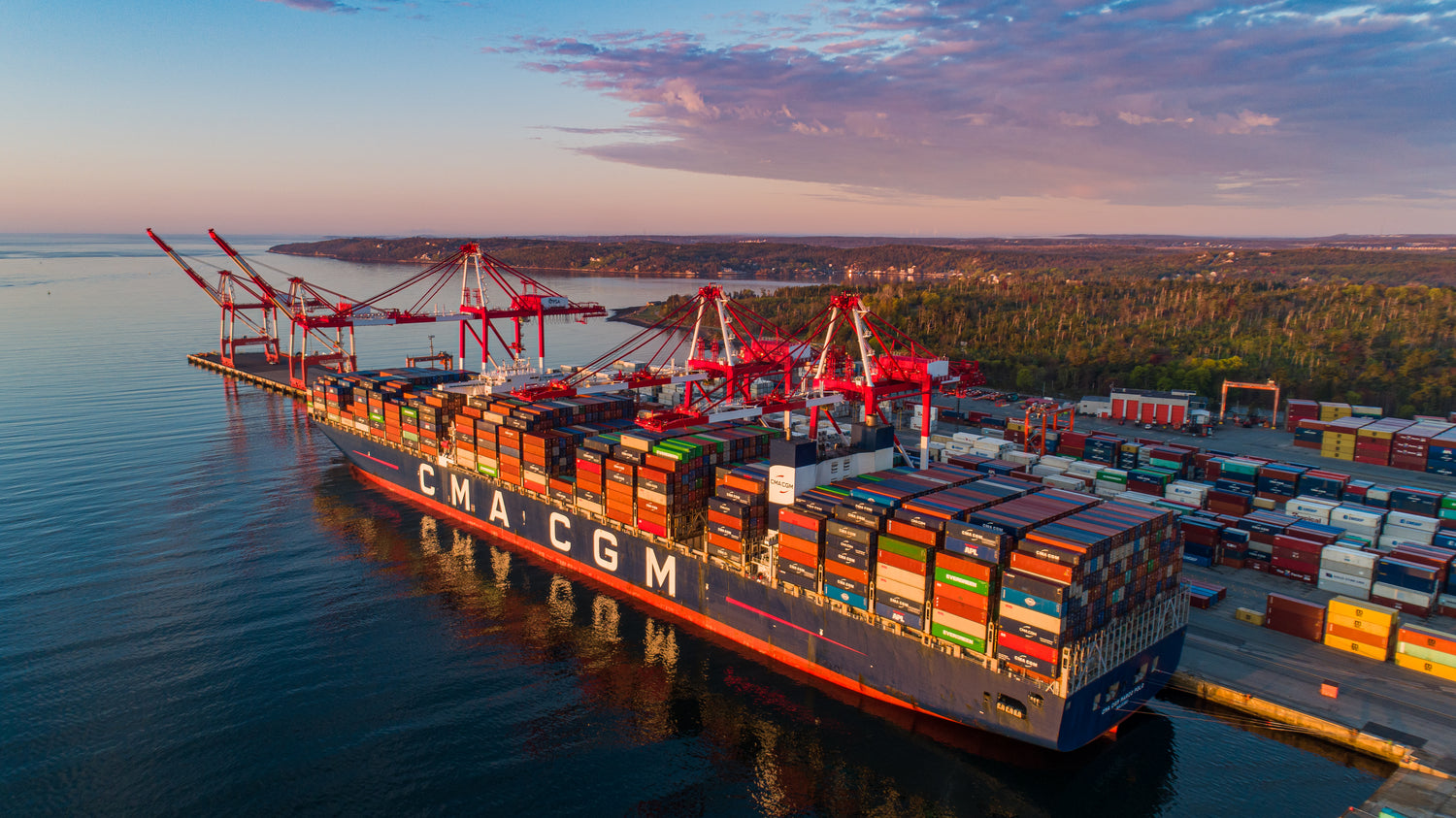 Wideshot aerial view of a cargo boat docked at sunset.