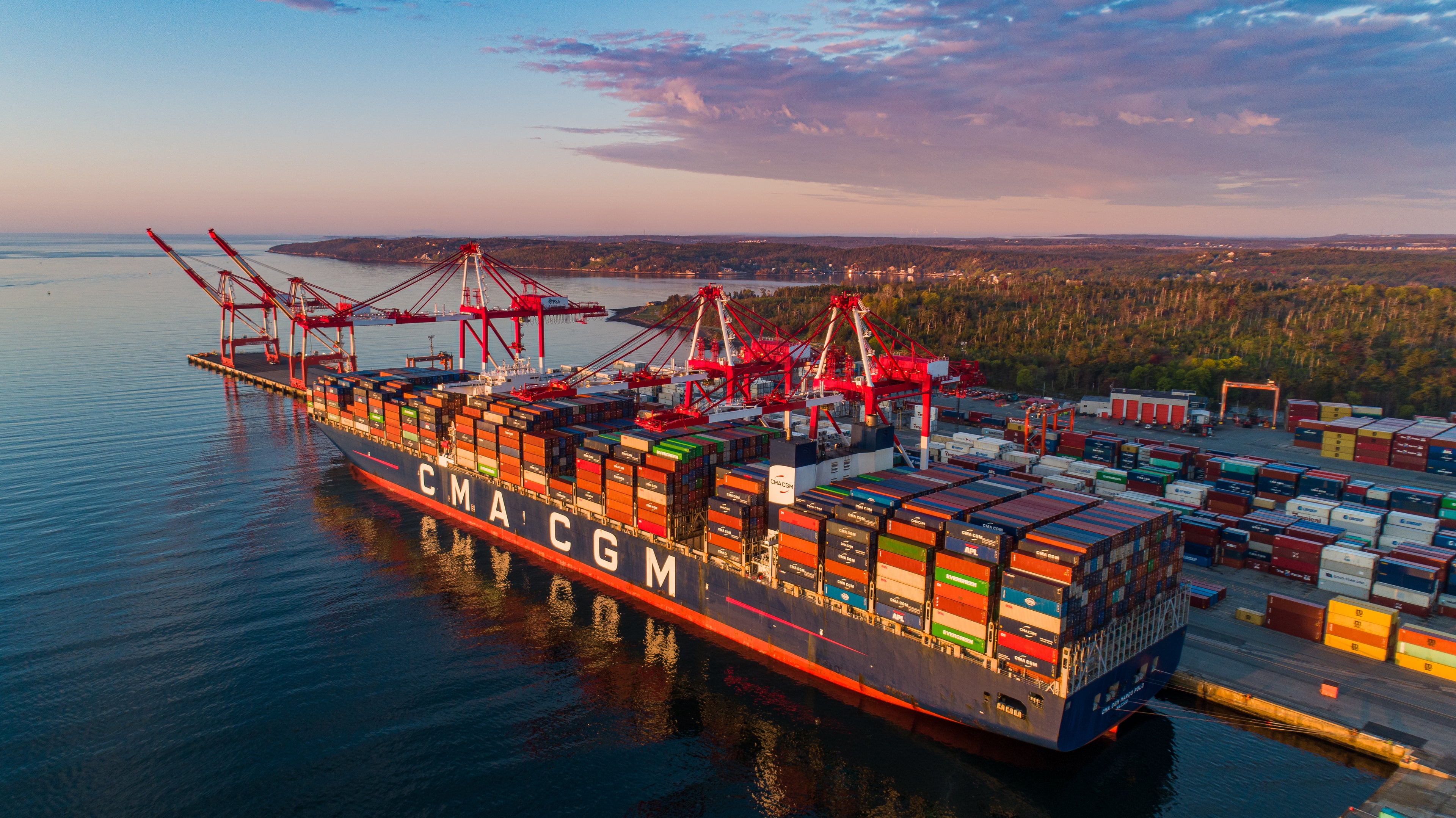 Wideshot aerial view of a cargo boat docked at sunset.