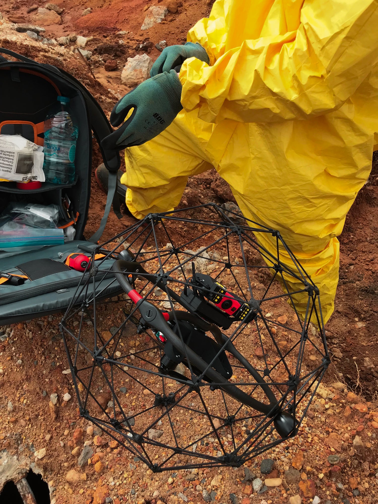 Person in yellow protective suit with an Eliios-3 on a rocky ground