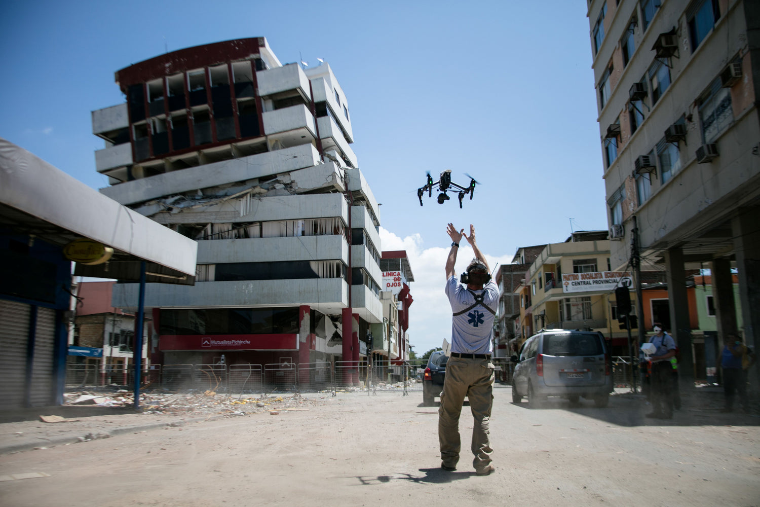 Person flying a drone in an urban area with damaged buildings