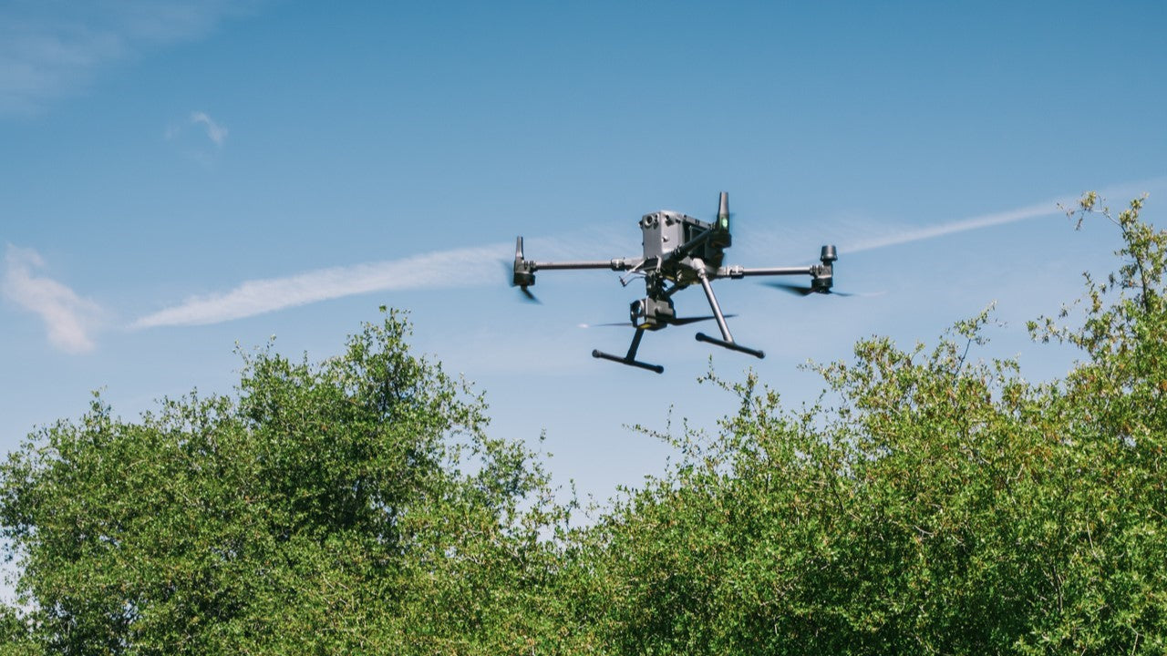 Drone flying in the sky with trees below