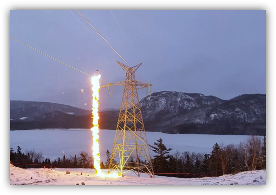 Zapped electrical tower in a snowy landscape with mountains in the background