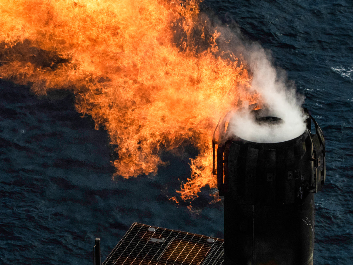 Flame and smoke emerging from a ship's stack against a dark ocean background