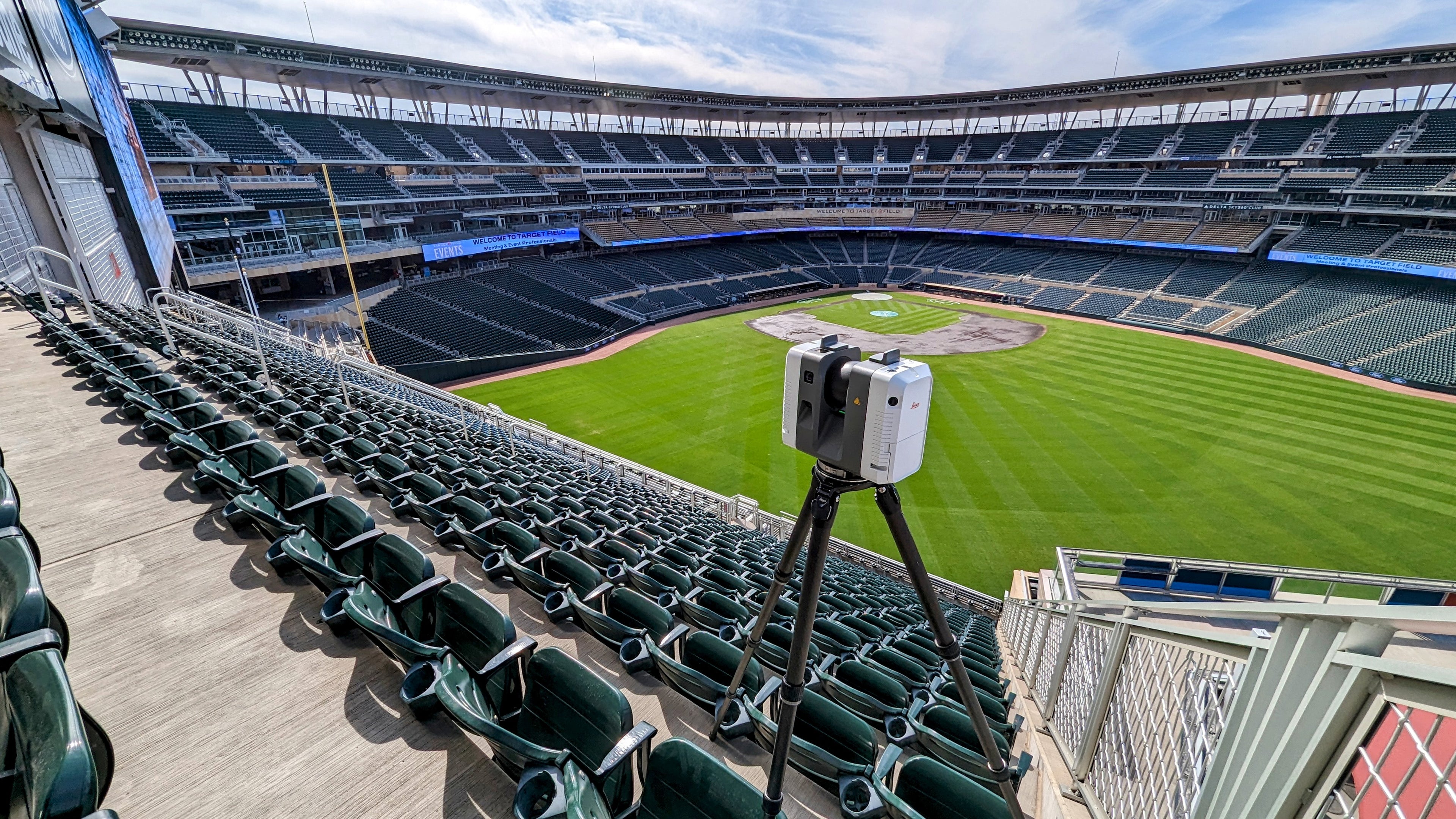Stadium with green seats and a scanner on a tripod facing the field